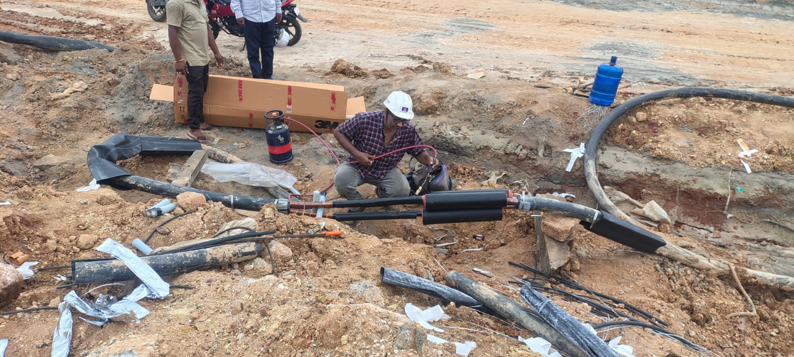 Jointer in a hard hat building an HT cable straight-through joint in an open trench using a 3M jointing kit